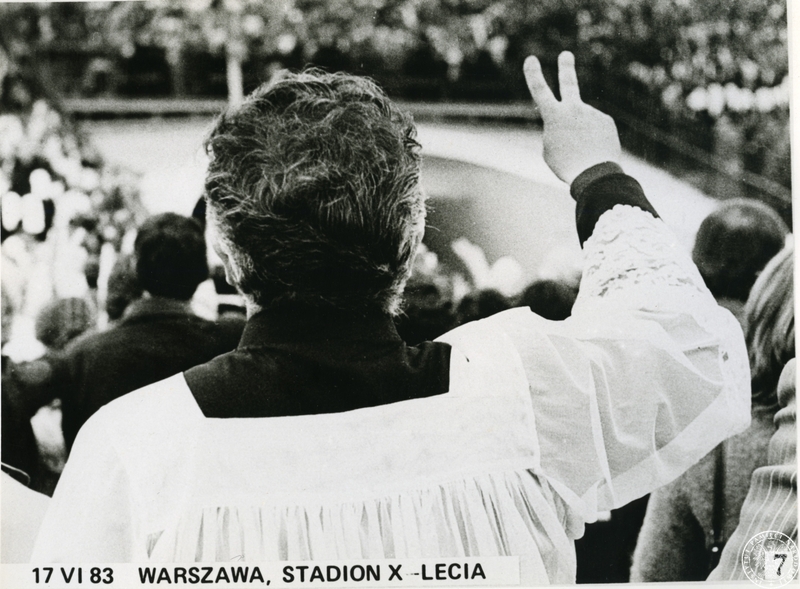Fot. nr 2. Ksiądz z ręką uniesioną w geście zwycięstwa na płycie Stadionu X-lecia. 17 VI 1983 r. Sygnatura:IPNGd-11-3-5-21