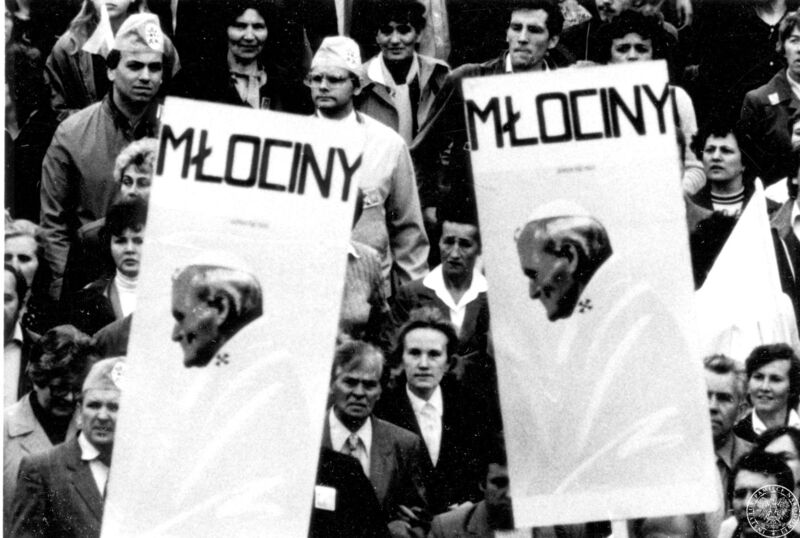 Fot. nr 9. Wierni na Placu Trzech Krzyży trzymający dwa transparenty ze zdjęciem Jana Pawła II i napisem "MŁOCINY" czekają na przejazd papieża. 17 VI 1983 r. Sygnatura: IPNBU-7-14-10-35