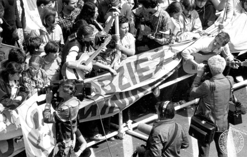 Fot. nr 16. Młodzież z Duszpasterstwa Dominikańskiego wokół częściowo zwiniętego transparentu "Młodzież Dominikańska" filmowana przez kamerę. Trzy osoby grają na gitarach. 17 VI 1983. Sygnatura: IPNBU-7-14-10-92