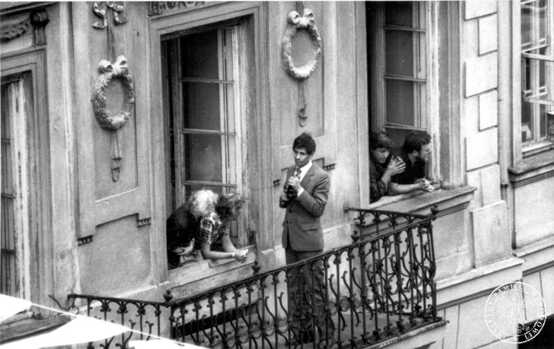 Fot. nr 19. Mężczyzna na balkonie i ludzie wyglądający przez okna kamienicy przy Placu Trzech Krzyży w oczekiwaniu na przejazd papieża. 17 VI 1983. Sygnatura: IPNBU-7-14-10-117