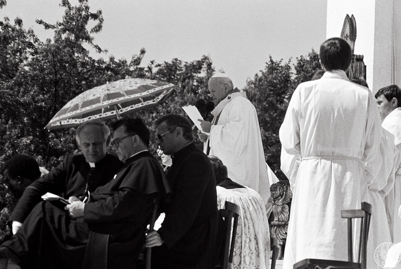 Fot. nr 14. Jan Paweł II (przemawia do mikrofonu) celebruje Mszę św. na hipodromie na Partynicach w otoczeniu służby liturgicznej. Z lewej trzech księży pod parasolem.  21 VI 1983 r.  Sygnatura: IPNBU-7-14-13-720