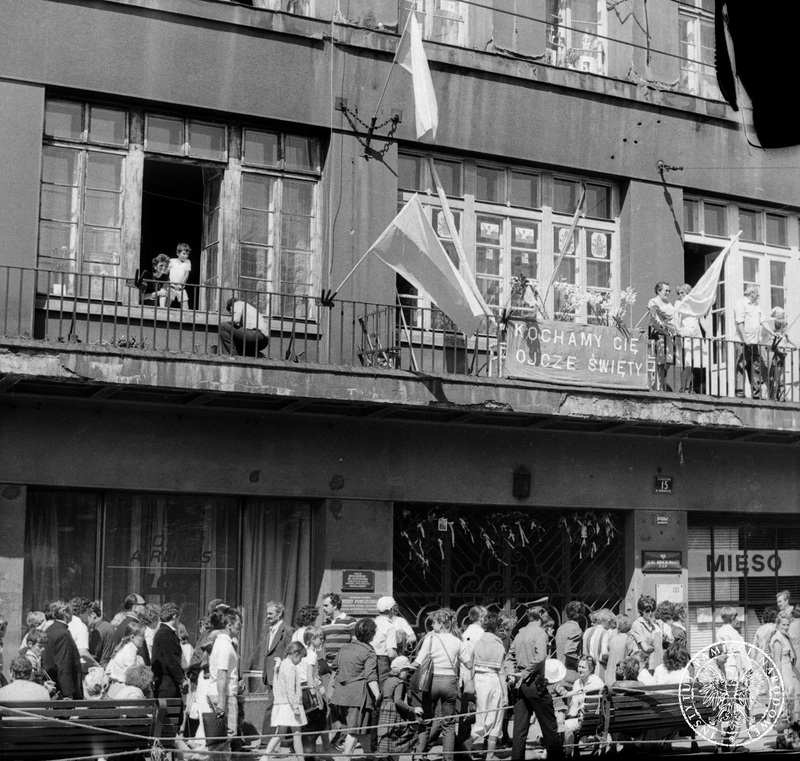 Fot. nr 8. Budynek przy ul. Basztowej 15  przystrojony flagami i transparentem „Kochamy Cię Ojcze Święty”. Na balkonach i oknach wierni. 22 VI 1983 r. Sygnatura: IPN Rz 739/1/33